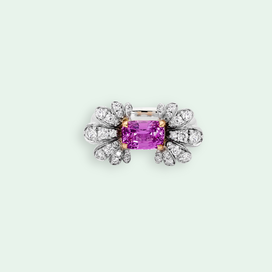Diamond-encrusted ring with a pink gemstone on a light gray background